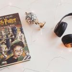 Minimalist setup with Harry Potter book, headphones, and string lights for a cozy reading experience.
